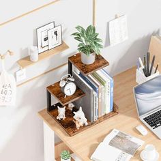 a laptop computer sitting on top of a wooden desk next to a potted plant