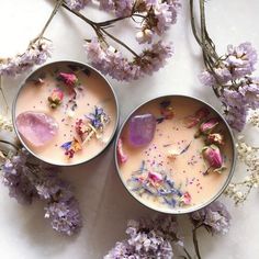 two bowls filled with different types of flowers on top of a white table next to purple flowers