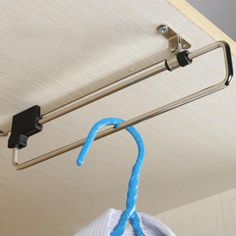 a blue object is hanging from a metal hook on the ceiling in front of a white wall