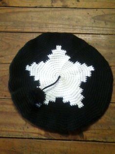 a black and white knitted hat with a clock on the front, sitting on a wooden floor