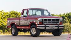 a red pick up truck parked in front of some trees