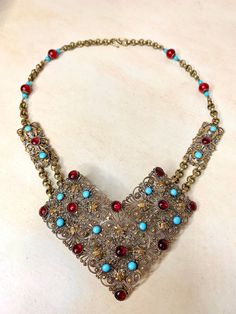 "Stunning vintage Edwardian era gilt brass filigree necklace. This gorgeous necklace was designed around a former antique sash belt. It was carefully deconstructed and refashioned into a dramatic necklace.  The large curved, dimensional filigree focal pendant is set with blue and red bezel set stones. It measures a grand 4-1/2\" x 3-1/2\". I added the original rectangular panels and linked them with textured brass chain.  I added vintage Cherry Tree brand beads to match the existing beads in the Vintage Antique Gold Festive Jewelry, Vintage Antique Gold Jewelry For Festive Occasion, Red Victorian Jewelry For Vintage Collection, Vintage Bronze Necklace With Intricate Design, Vintage Ceremonial Necklace With Antique Finish, Vintage Gold Necklaces With Patina, Vintage Antique Finish Necklace For Ceremonial Occasion, Ceremonial Vintage Necklace With Antique Finish, Vintage Blue Ceremonial Jewelry