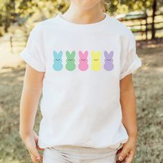 Colorful Easter Peeps t-shirts for your toddler or child! FEATURES * Rabbit Skins 4.5 oz., 100% combed ringspun cotton fine jersey t-shirt * Preshrunk, soft-washed, garment-dyed fabric * Design is printed on a white t-shirt * Printed with a direct to garment printer (DTG) - ink is printed into the fibers of the fabric for long-lasting wear that never fades! * Fast shipping (3-5 business days) * Beautifully packaged, and ready to gift for any special occasion! * All items are produced in Hartland Playful Easter Short Sleeve T-shirt, Easter Graphic Print Playful Tops, Playful Easter Tops With Graphic Print, Cute Short Sleeve Easter T-shirt, Playful Short Sleeve Tops For Easter, Easter Bunny Print Cotton Tops, Cute Crew Neck Easter Tops, Playful White Pre-shrunk Shirt, Cotton Bunny Print Top For Easter