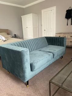 a blue velvet couch in a bedroom next to a bed