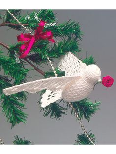 a white bird ornament with a red rose in it's beak hanging from a christmas tree