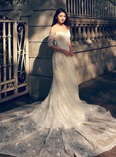 a woman is standing in front of a gate wearing a wedding dress and posing for the camera