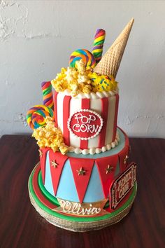 a large cake decorated with candy, popcorn, and ice cream on top of a wooden table