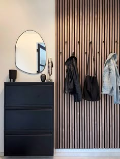 a black dresser sitting next to a mirror and coat rack