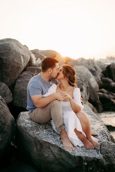 a man and woman sitting on rocks kissing