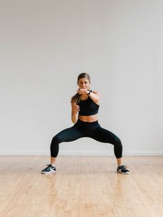 a woman in black sports bra top and leggings standing on one leg while holding a