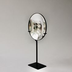 a round mirror sitting on top of a metal stand