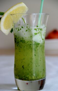 a green drink with lemon wedges in it