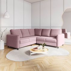 a living room with a pink sectional couch and coffee table in the corner on a wooden floor