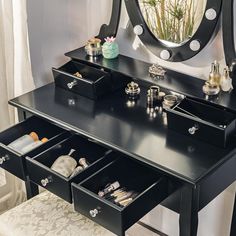 a black vanity with drawers underneath a mirror