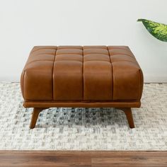 a brown leather ottoman sitting on top of a rug