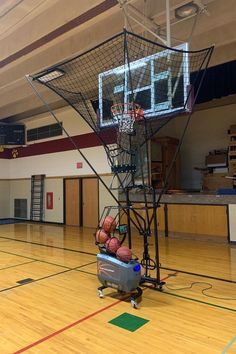 a basketball goal in the middle of a gym with balls on it and a basket