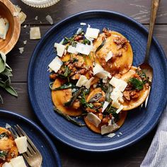 two blue plates filled with food on top of a wooden table next to utensils