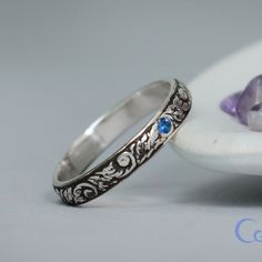 two silver rings with blue stones sitting on top of a white plate next to a flower