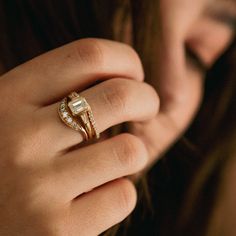 a close up of a person's hand wearing a gold ring with diamonds on it