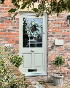 a green door with a wreath on the glass and some plants in front of it