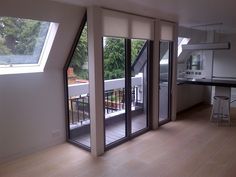 an empty room with sliding glass doors leading to the kitchen and dining area in the background