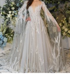 a woman in a wedding dress standing next to a floral wall with flowers on it