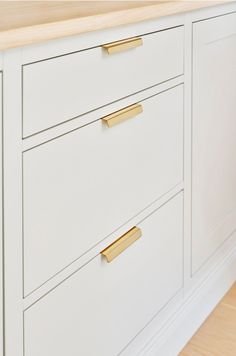 a white kitchen with gold handles and drawers