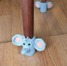 a crocheted elephant is standing under a wooden pole with its trunk sticking out