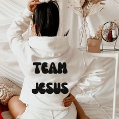 *RECOMMEND SIZING UP TO LOOK OVERSIZED* Team Jesus Sweatshirt ,Aesthetic Sweatshirt, Oversized Sweatshirt, Pinterest Hoodie, Words On Back, Hoodie, VSCO, Trendy Hoodie, Tumblr Hoodie, Aesthetic Hoodie, Perfect gift, Aesthetic Clothes Trendy Y2k **Words are printed on the back of the sweatshirt** Gildan Unisex Sweatshirt, Hoodie 50% Cotton 50% Polyester Medium-heavy fabric (8.0 oz/yd² (271.25 g/m ✔Make sure you check our size-chart before you place your order. We have size chart on our listing ph White Slogan Crew Neck Hoodie, White Hoodie With Lettering In Relaxed Fit, White Cotton Hoodie With Team Name, White Crew Neck Hoodie With Slogan, White Text Print Hoodie Tops, White Cotton Team Hoodie, White Text Print Hoodie, White Hoodie With Letter Print For Team Spirit, White Team Spirit Hoodie Sweatshirt