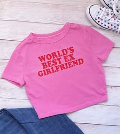 NEW! "World's Best Ex Girlfriend" Crop Top/Baby Tee is perfect for YOU!  This simple design says it all, without saying too much. It is perfect with your favorite pair of jeans or that cute mini skirt! High heels or tennis shoes, you can't go wrong with this baby tee!  Order a size up for a loose fit.  Machine wash is okay! Please HANG DRY! T-shirts are hand dyed and can slightly bleed after the first wash. Please wash with like colors. Design should outlast the t-shirt but if there is any lifting of the decal, cover design with parchment paper and press with a hot iron. Cute Pink Slogan Tops, Fitted Pink Tops With Letter Print, Trendy Pink T-shirt With Name Print, Pink Cotton Tops With Letter Print, Cute Cotton Slogan Tops, Cute Cotton Tops With Slogan, Cute Cotton Tops With Name Print, Pink Fun Top With Text Print, Basic Pink Slogan Top