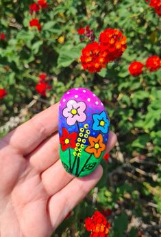 a hand holding an easter egg with flowers painted on it