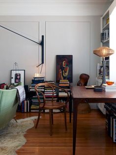 a living room filled with lots of furniture and books on top of a hard wood floor