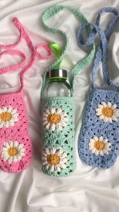 three crocheted water bottles are laying on a white sheet and one has a green bottle in it