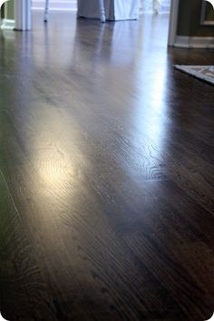 an empty room with wooden floors and white curtains