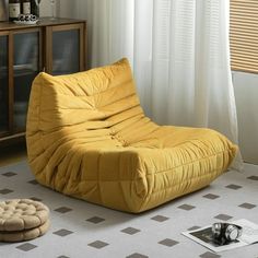 a yellow bean bag chair sitting on top of a white rug next to a window