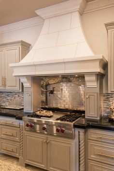 a stove top oven sitting inside of a kitchen next to white cabinets and counter tops