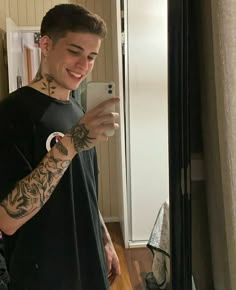 a man taking a selfie with his cell phone in front of him and tattoos on his arm