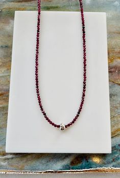 This necklace combines  a beautiful deep wine red strand of tiny faceted red garnet beads with a large holed, hammered sterling silver bead that floats or slides over the garnet beads. Strung on a sterling silver lobster clasp.  This little necklace gives you a lot of bang for your buck with a bright pop of color and a flash of silver.it can easily be worn dressed up or down.  Measures approximately 16-18 inches  Stone beads measure approximately 2-2.5mm Silver bead measures approximately 5 x 8mm Matching accessories available.  Inquire for custom orders. Faceted Round Bead Sterling Silver Necklace, Sterling Silver Rondelle Necklace With Faceted Beads, Sterling Silver Necklace With Faceted Rondelle Beads, Sterling Silver Rondelle Gemstone Beaded Necklace, Bright Pop, Hammered Sterling Silver, Matching Accessories, Silver Bead, Garnet Gemstone