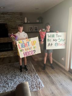 two people holding up signs in front of a fireplace with the words will you light up my night at hoo?