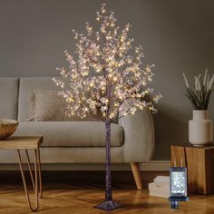 a lighted tree in a living room next to a couch