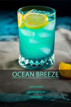 a blue curacao cocktail with lemon wedges on the side and text ocean breeze