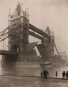 an old photo of people standing in front of the tower bridge