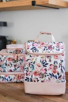 three floral suitcases sitting on top of a wooden table