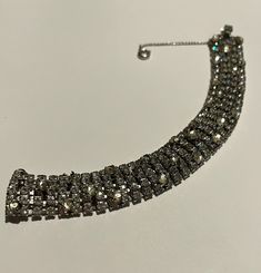 This bracelet measures 6 1/2 inches in length and is 3/4 inch in width.  It displays five rows of round, clear sparkling rhinestones prong-set into silver tone metal.  Several larger rhinestones decorate the top of the bracelet.  The bracelet has a chain guard and a tongue and groove closure.  The closure is signed "Sandor". Silver Crystal Bracelets With Rhinestones, Dazzling Bling Crystal Bracelet, Silver Sparkling Crystal Bracelet, Glamorous Crystal Bracelet With Rhinestones, Glamorous Crystal Bracelets With Rhinestones, Silver Crystal Embellished Bracelet For Party, Dazzling Silver Crystal Bracelet With Bling, Sparkling Silver Crystal Bracelet, Diamond Crystal Bracelet With Rhinestones For Party