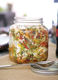 a glass jar filled with lots of food next to a bottle of wine on top of a table