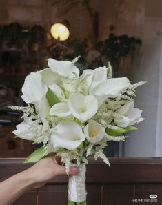 a bouquet of white flowers is being held by a person