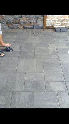 a man standing on top of a sidewalk next to a white dog wearing flip flops