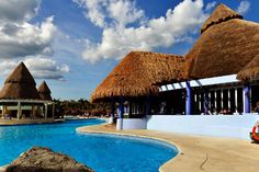 an outdoor swimming pool with thatched roof huts