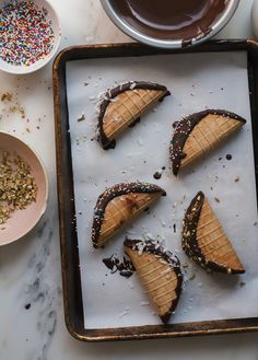 some desserts are on a baking sheet with chocolate sauce and sprinkles