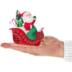 a hand holding a small santa clause on a sleigh